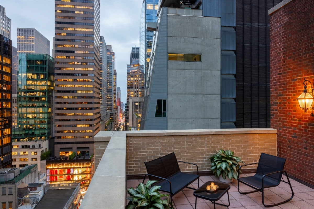 a rooftop patio with chairs and plants