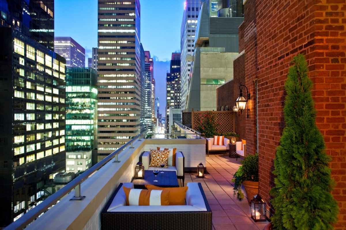 a rooftop patio with chairs and tables in a city