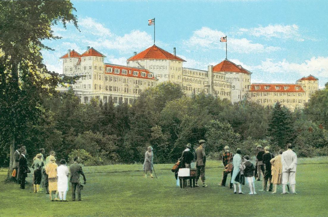 a group of people standing in a grassy area with a large building in the background