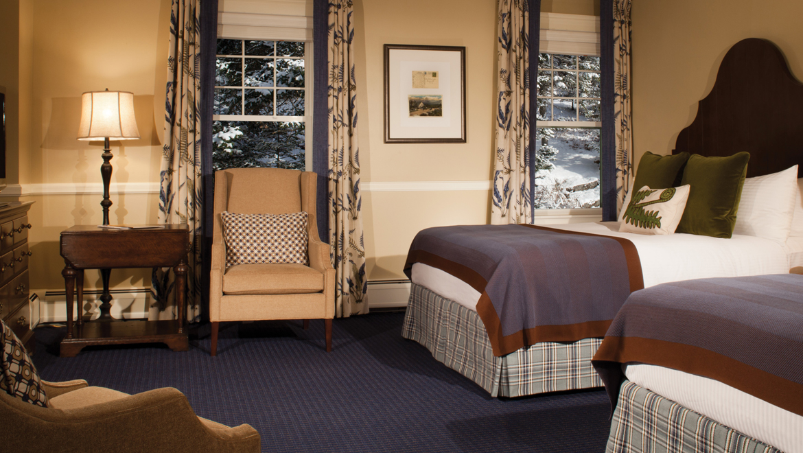 a room with two beds and a chair
