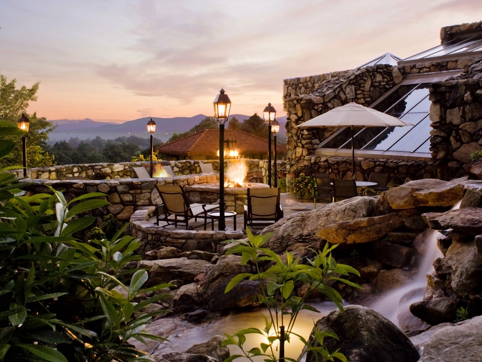 a patio with a fire pit and a waterfall
