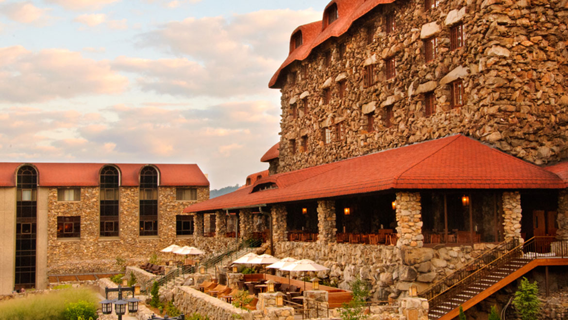 a stone building with red roof and tables and chairs