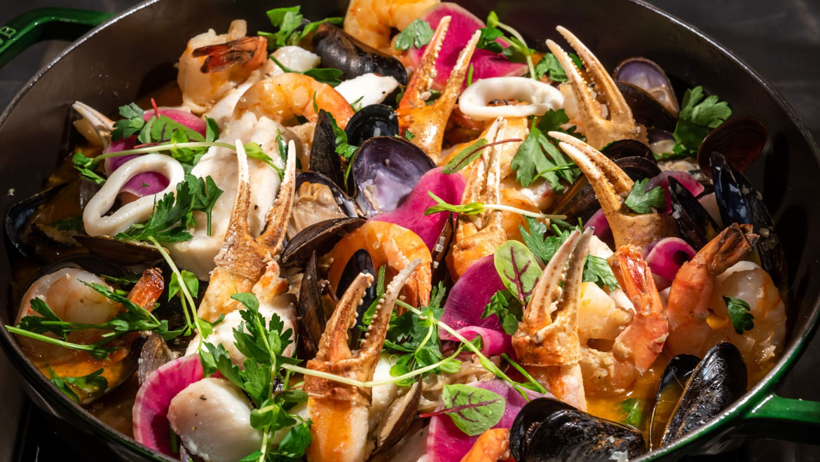 a bowl of seafood with claws and vegetables