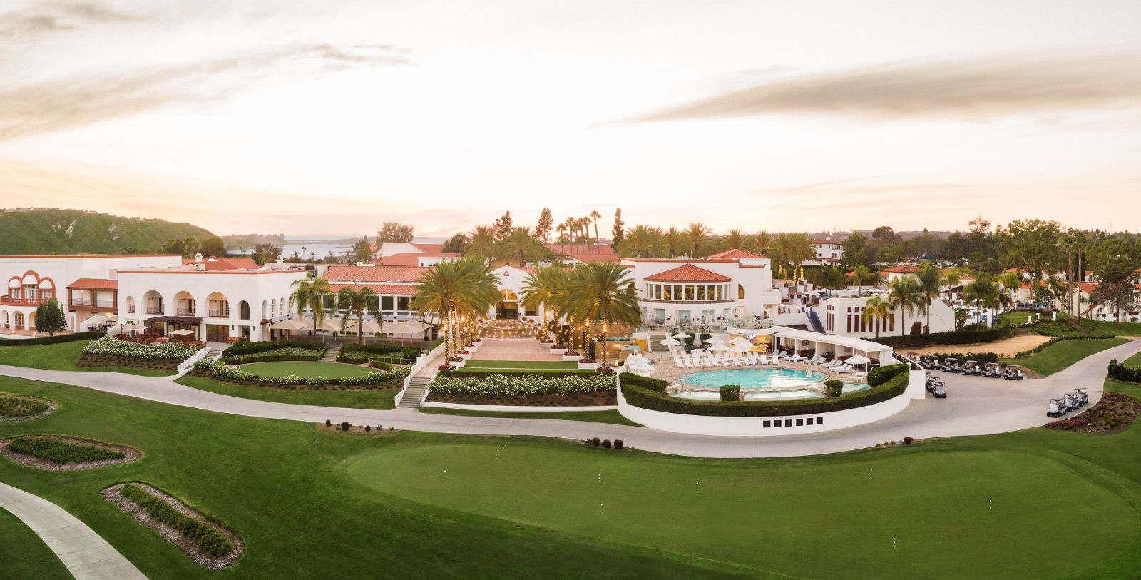 a large white building with a pool and palm trees