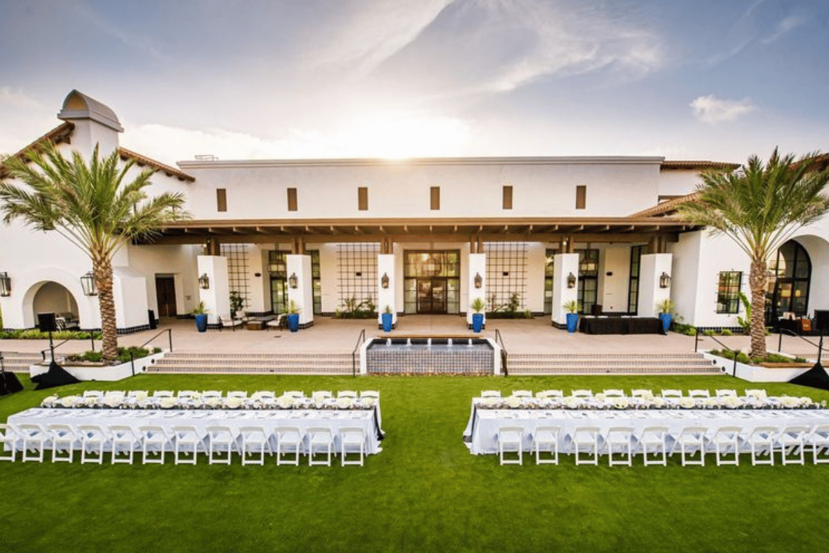 a large building with a lawn and tables with white chairs