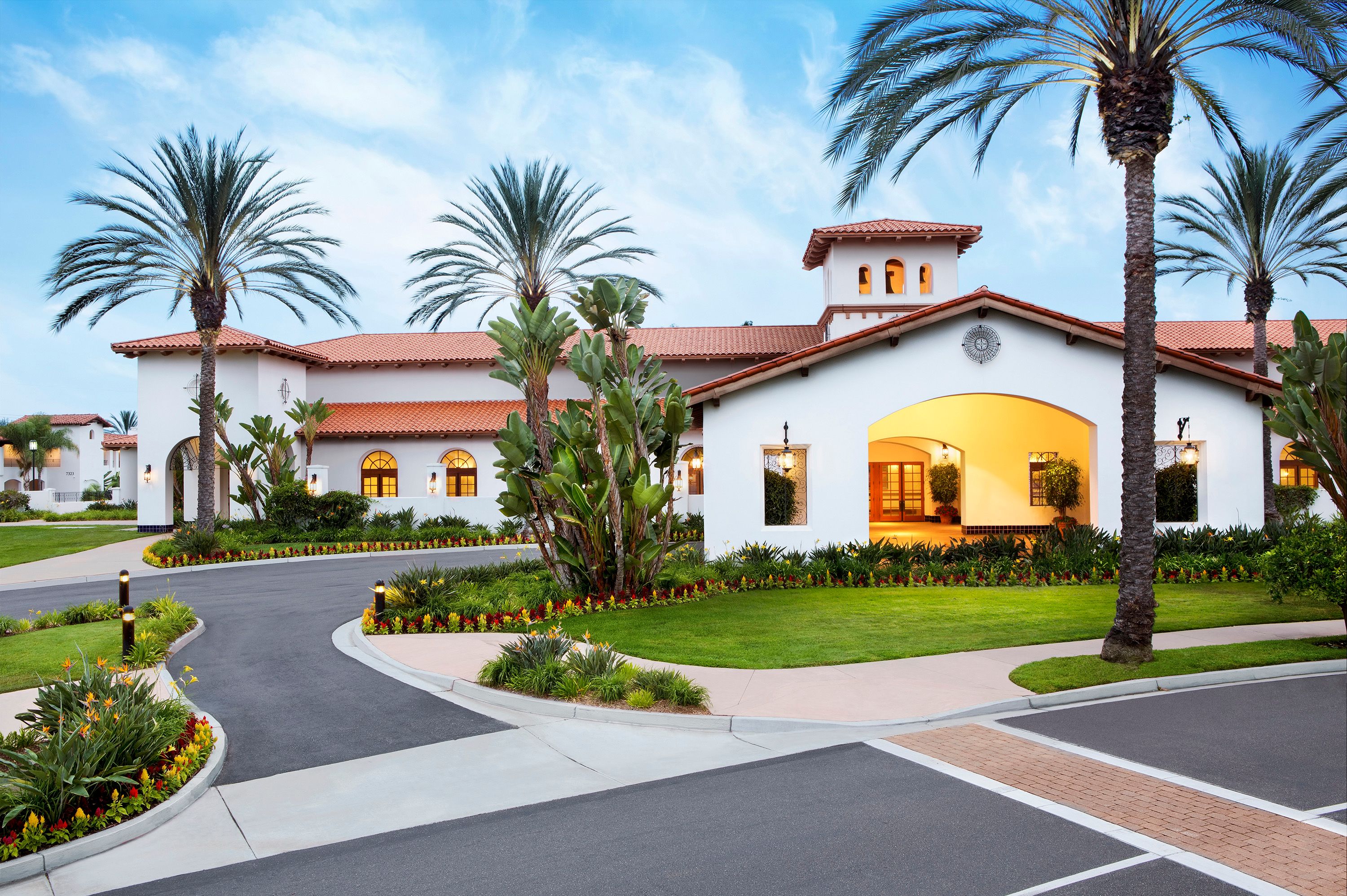 a white building with a large lawn and palm trees
