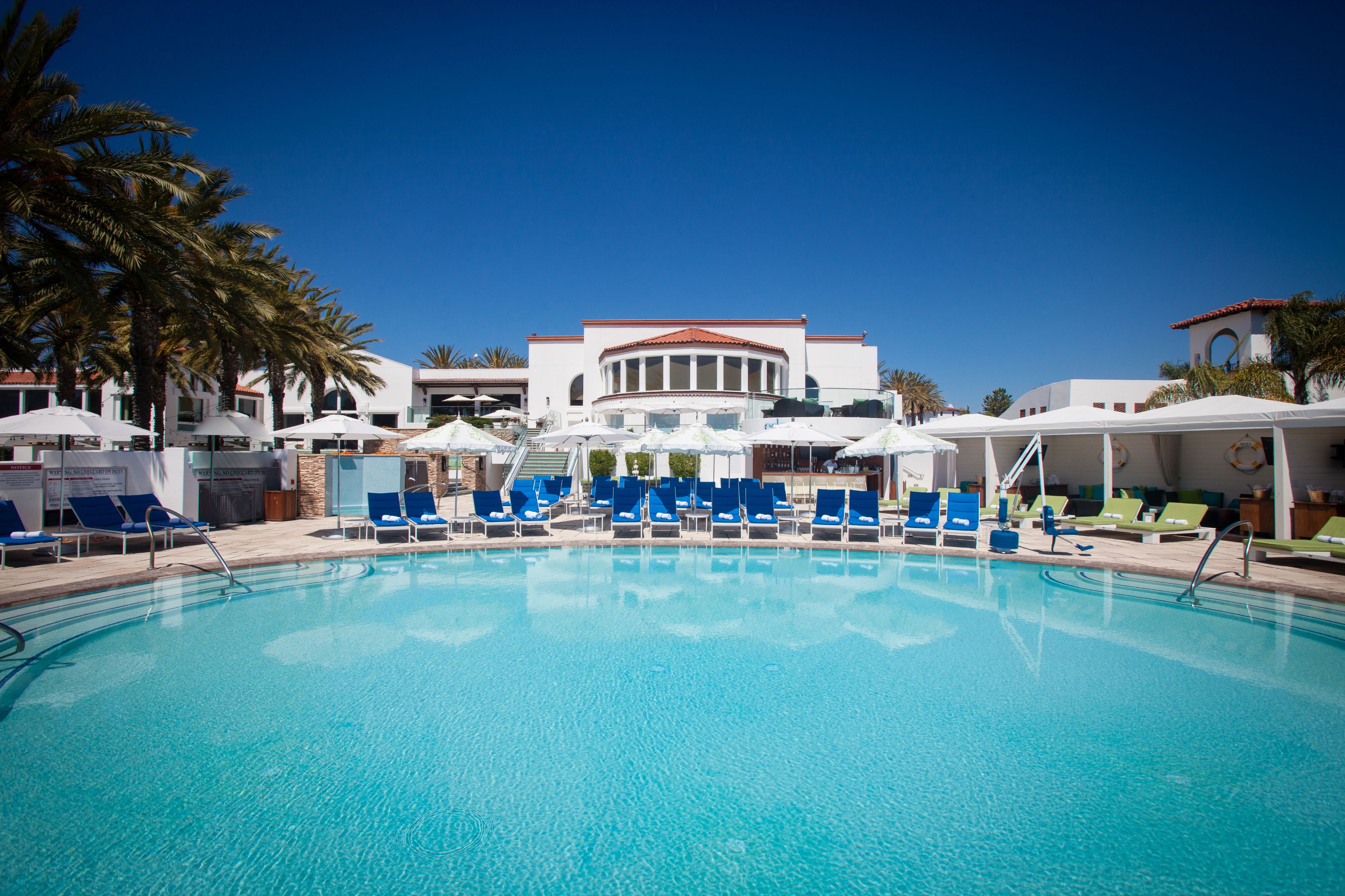 a pool with chairs and umbrellas in front of a building