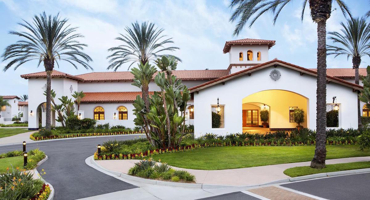 a white house with a circular driveway and palm trees