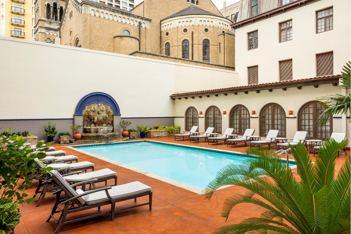 a pool with chairs and a fountain in the background