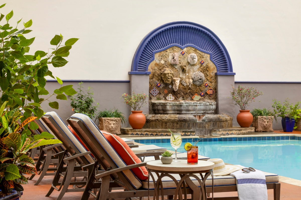 a pool with a fountain and chairs