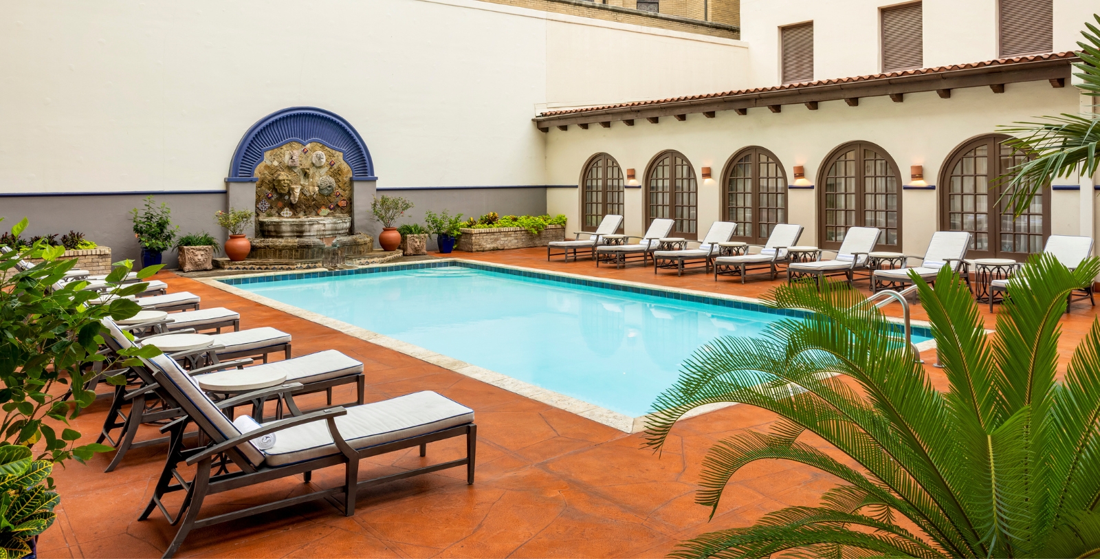 a pool with lounge chairs and a fountain