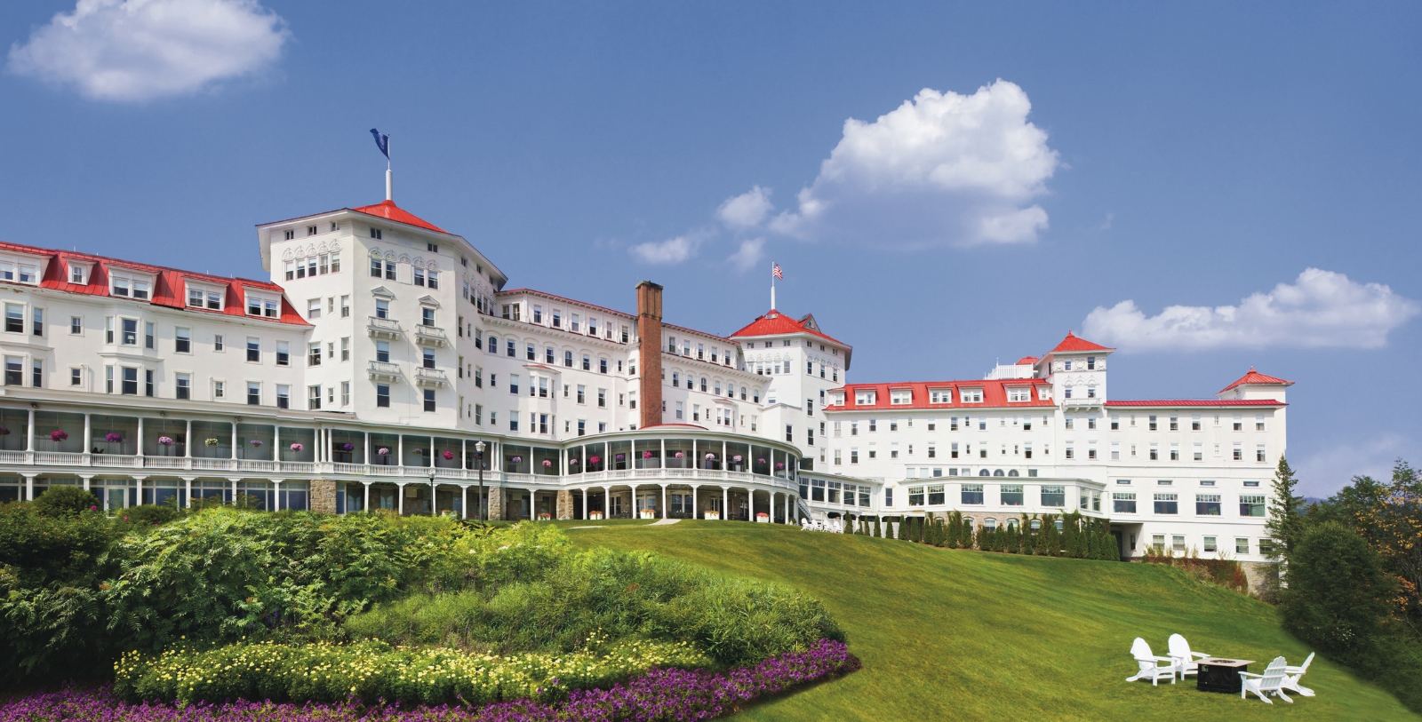 a large white building with red roofs with Mount Washington Hotel in the background
