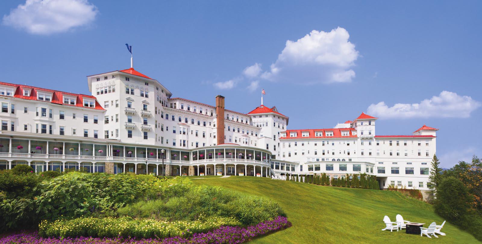 a large white building with red roofs with Mount Washington Hotel in the background