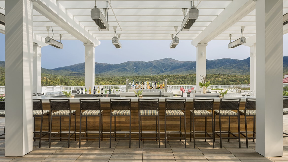 a bar with chairs and a view of mountains