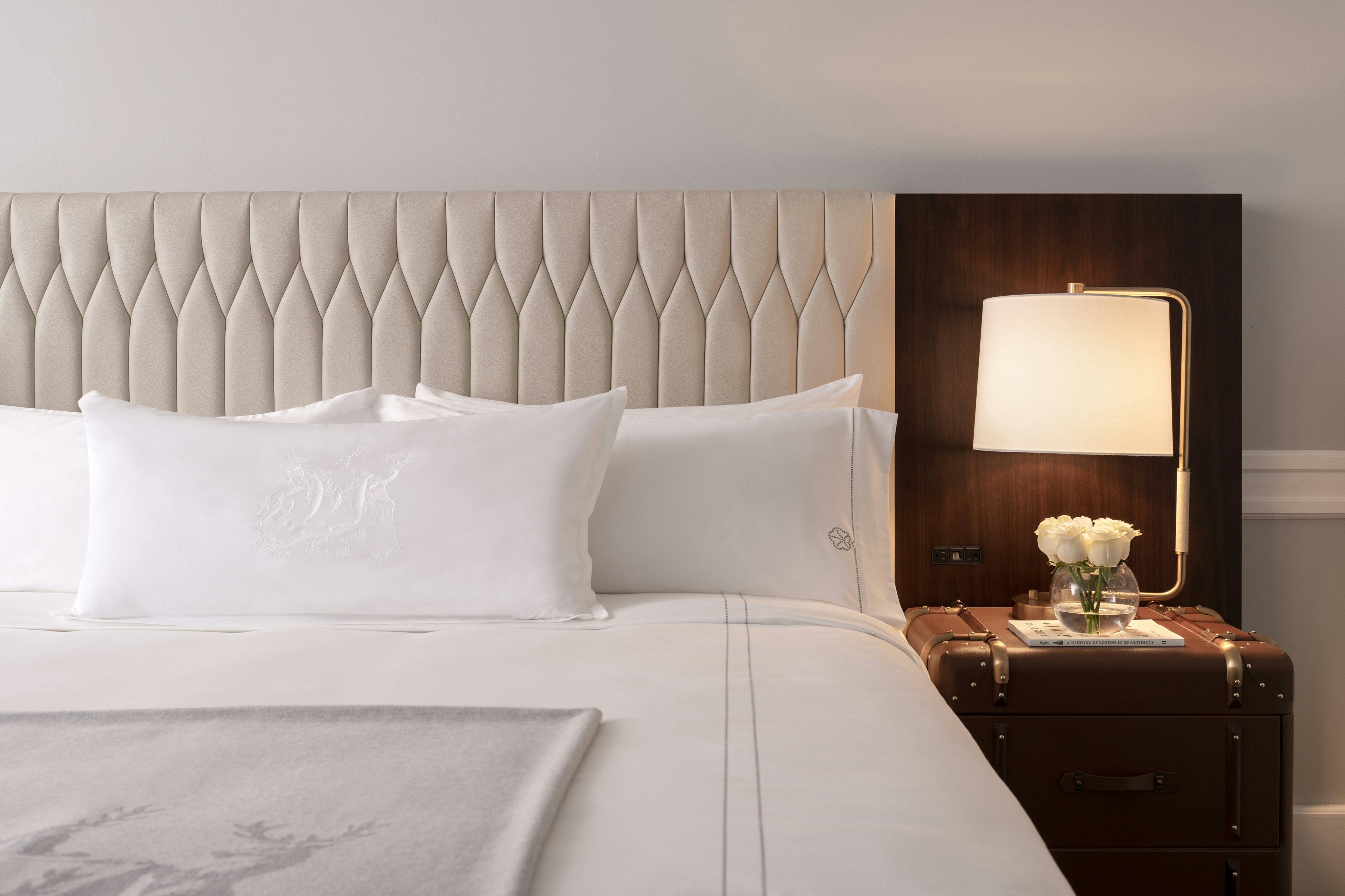a bed with a lamp and a flower on a nightstand