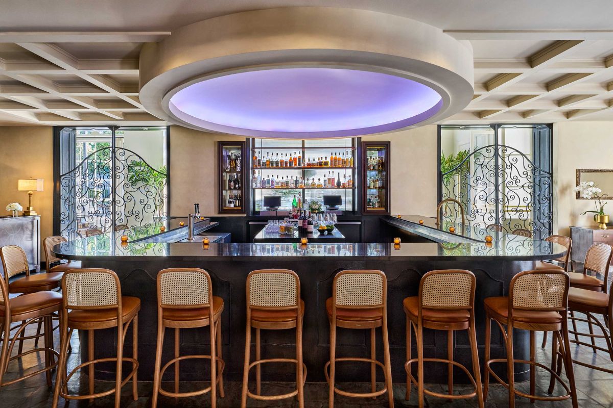 a bar with chairs and a shelf with drinks