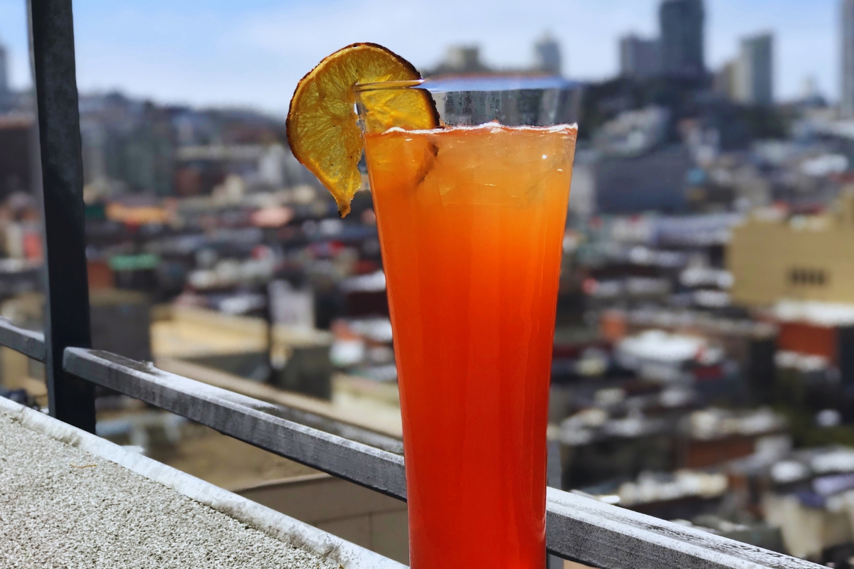 a glass of orange liquid with a slice of orange on top of it