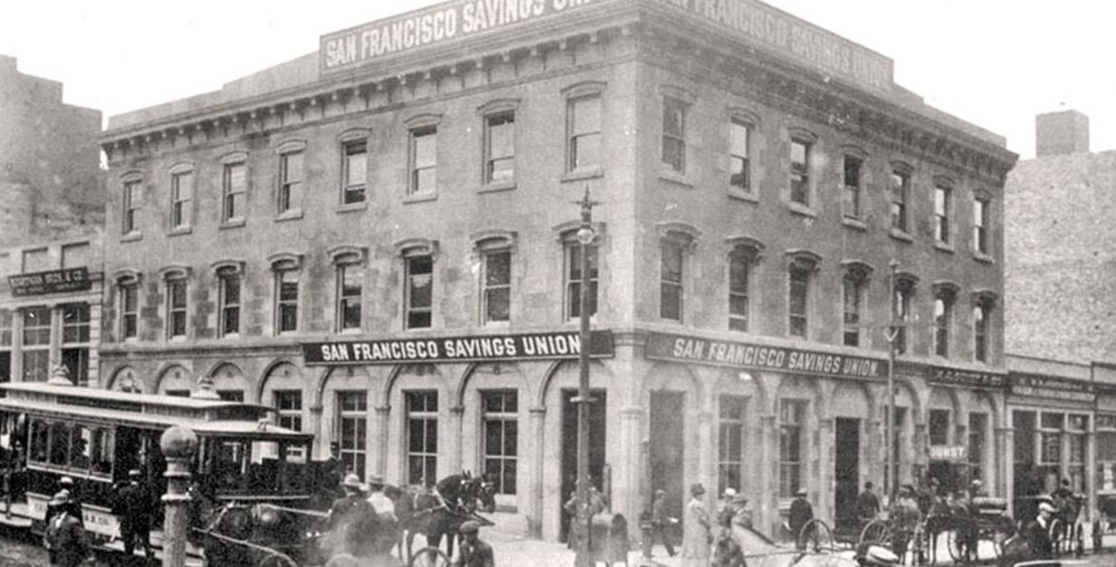 a black and white photo of a building with horse carriages