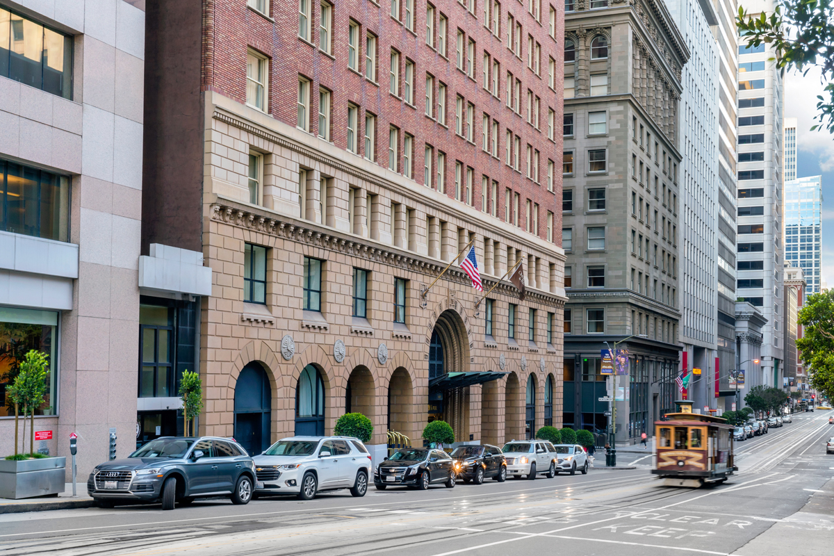 a street with cars and a trolley in front of a building