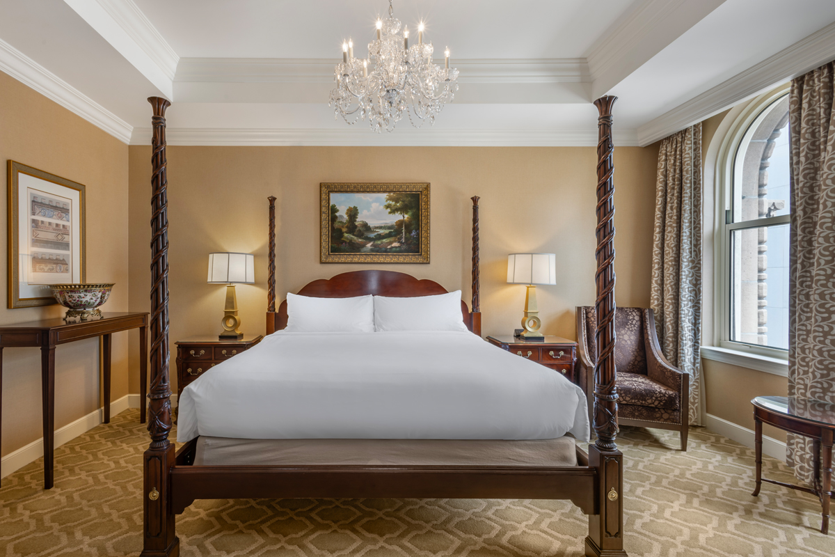 a bed with a chandelier and a painting on the wall