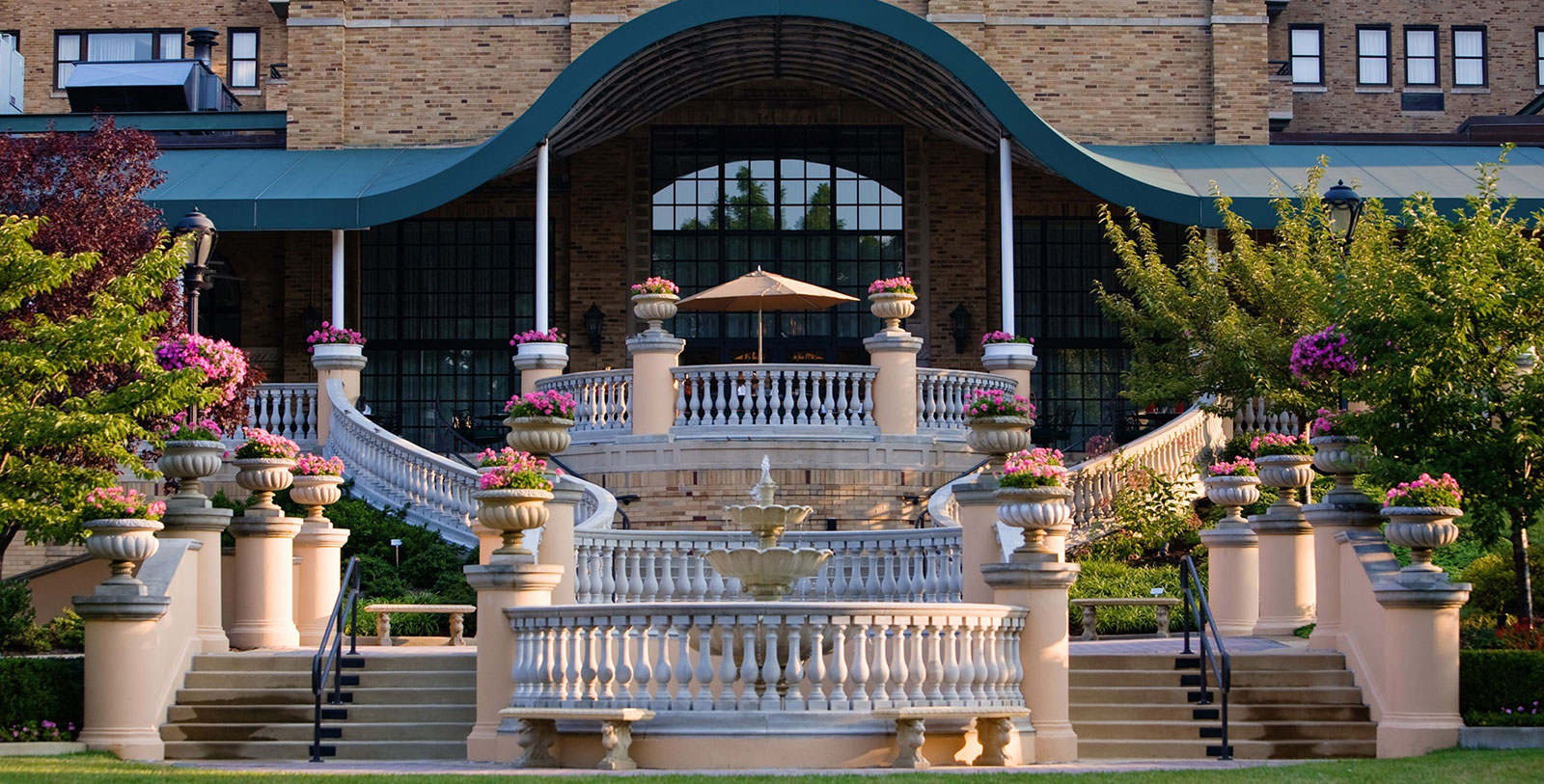 a large building with a fountain and flowers