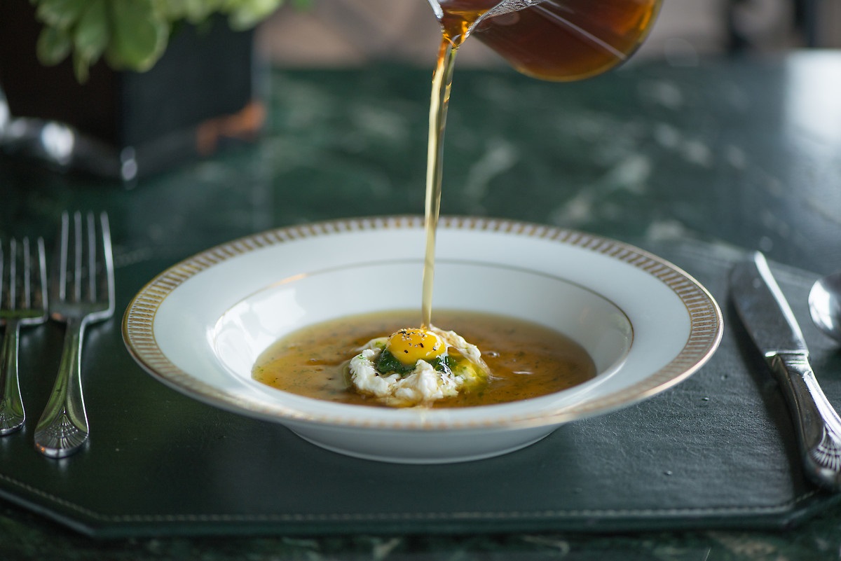 a bowl of soup with a egg and a yolk being poured into it