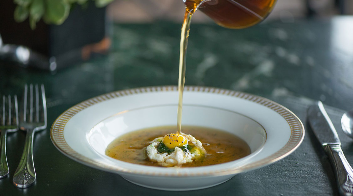 a bowl of soup with a yolk and a egg in it