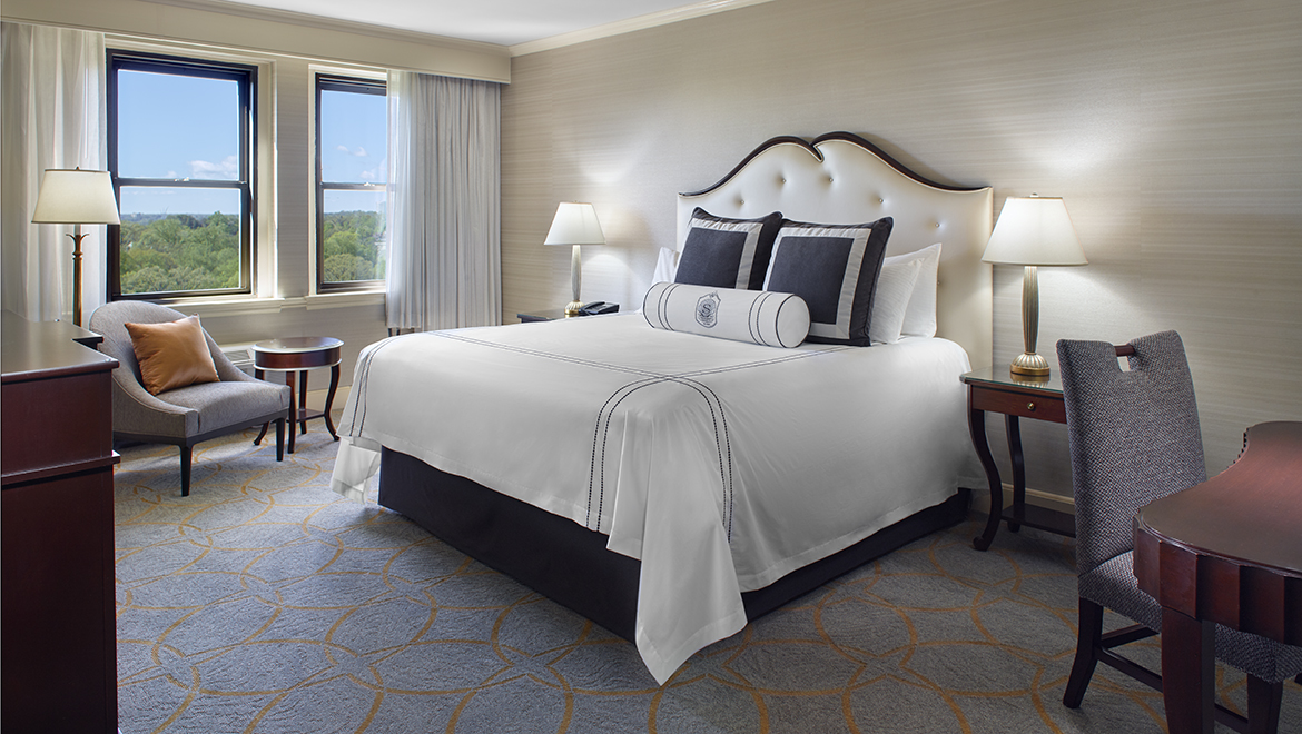 a bed with white sheets and pillows in a hotel room