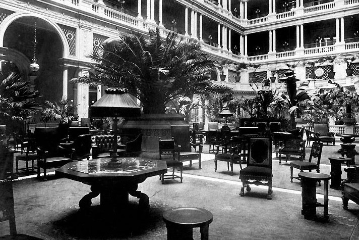a room with a large building with a large balcony and a large tree