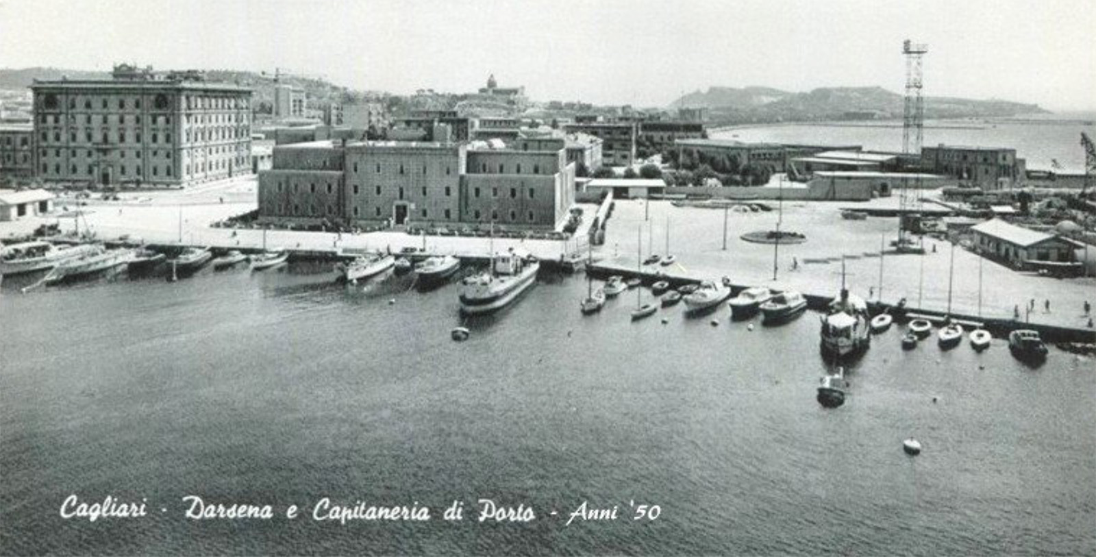 a black and white photo of a harbor with boats and buildings