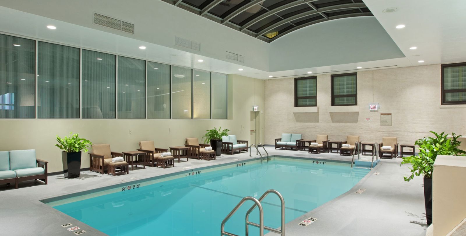 a swimming pool with chairs and a large stone wall