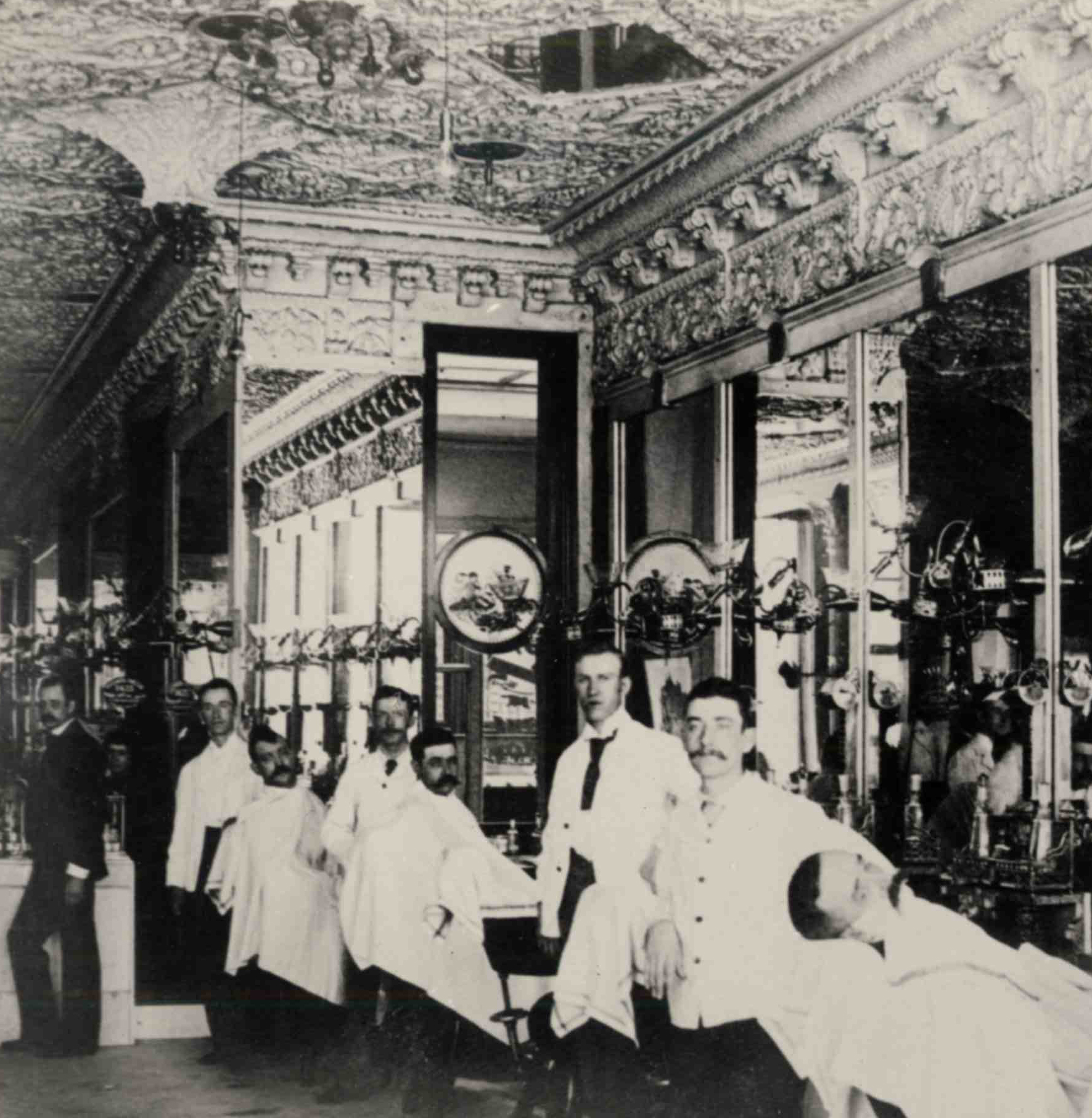 a group of men in white coats in a barber shop