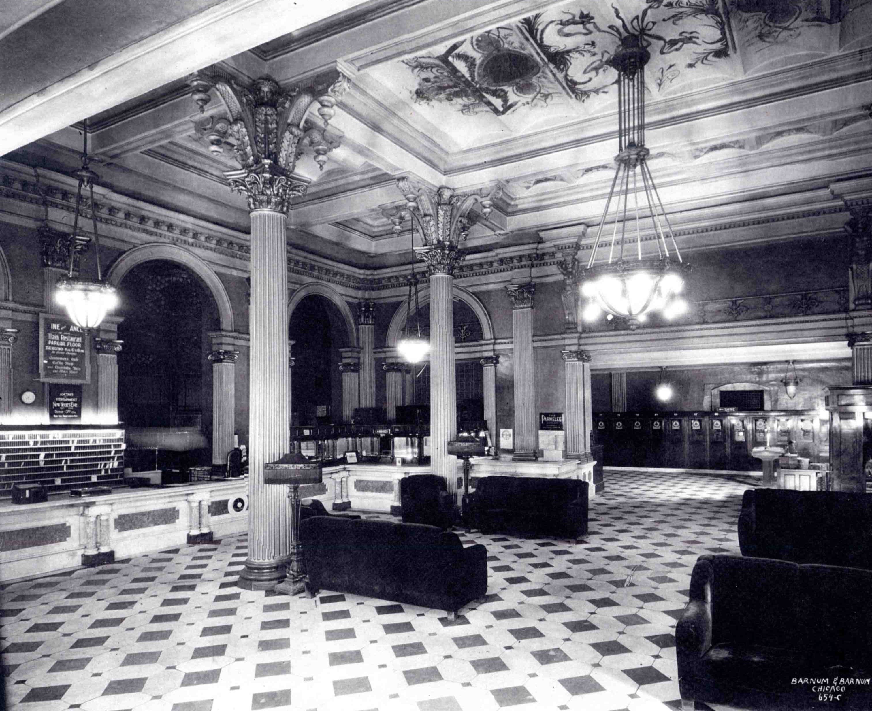a black and white photo of a room with columns and chairs