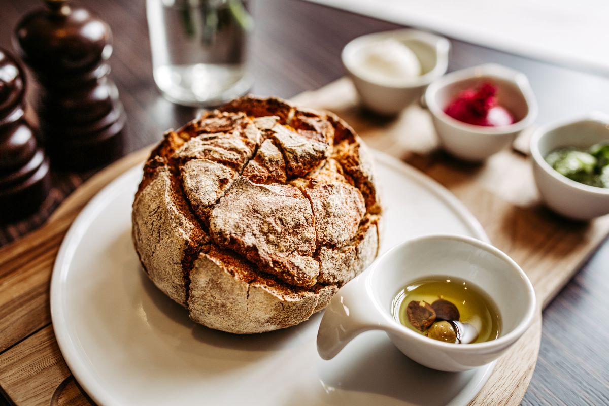 a round loaf of bread with a small white saucer on a white plate