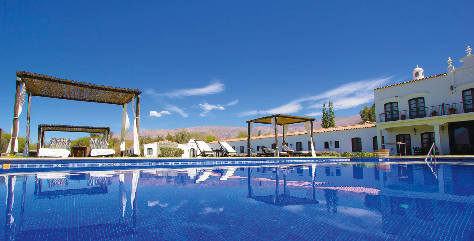 a pool with a white building and a white building with a blue sky