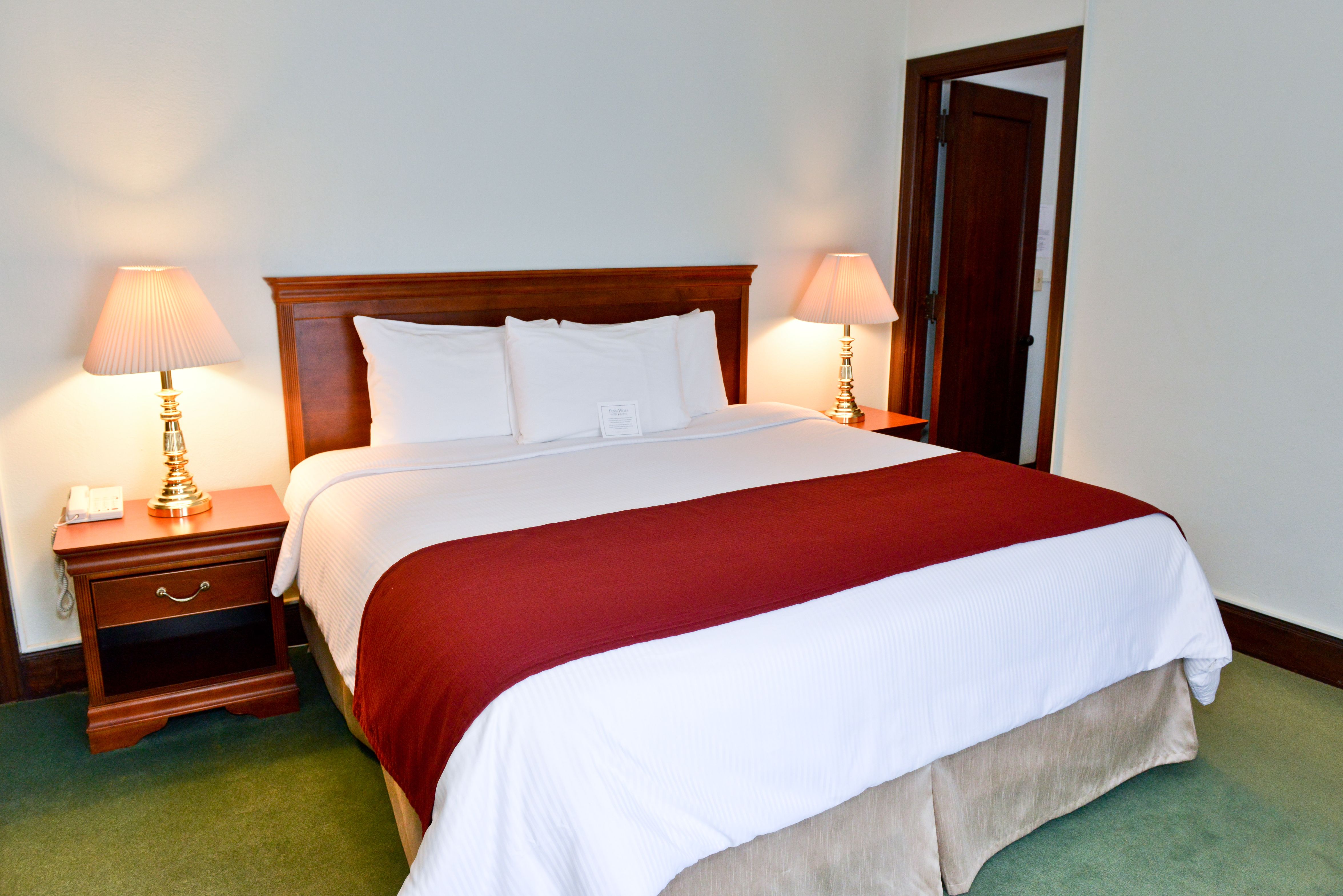 a bed with a red blanket and two lamps