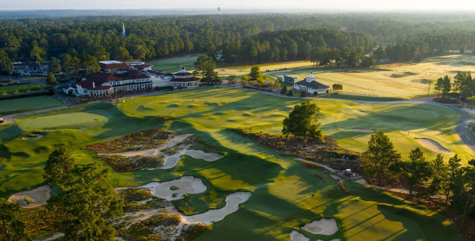 a golf course with a large building and sand bunkers