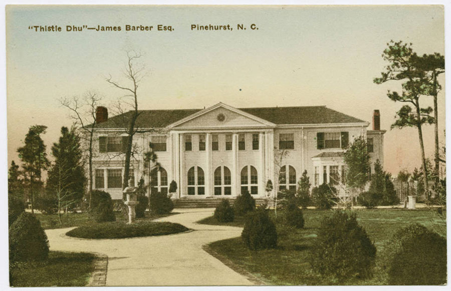 a large white building with a lawn and trees