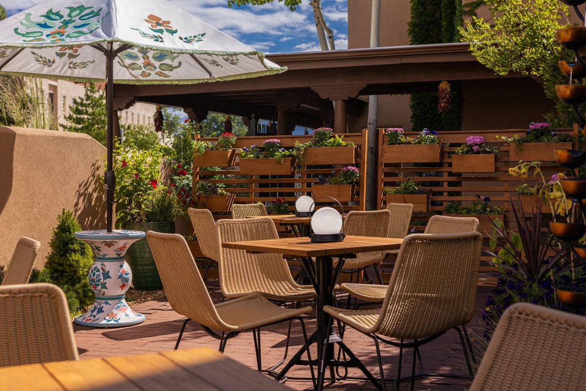 a table and chairs outside with a white umbrella