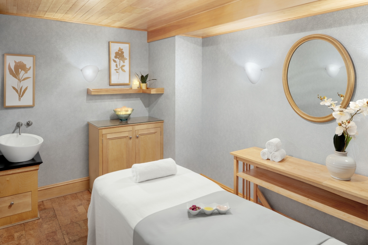 a massage room with a round mirror and a bed