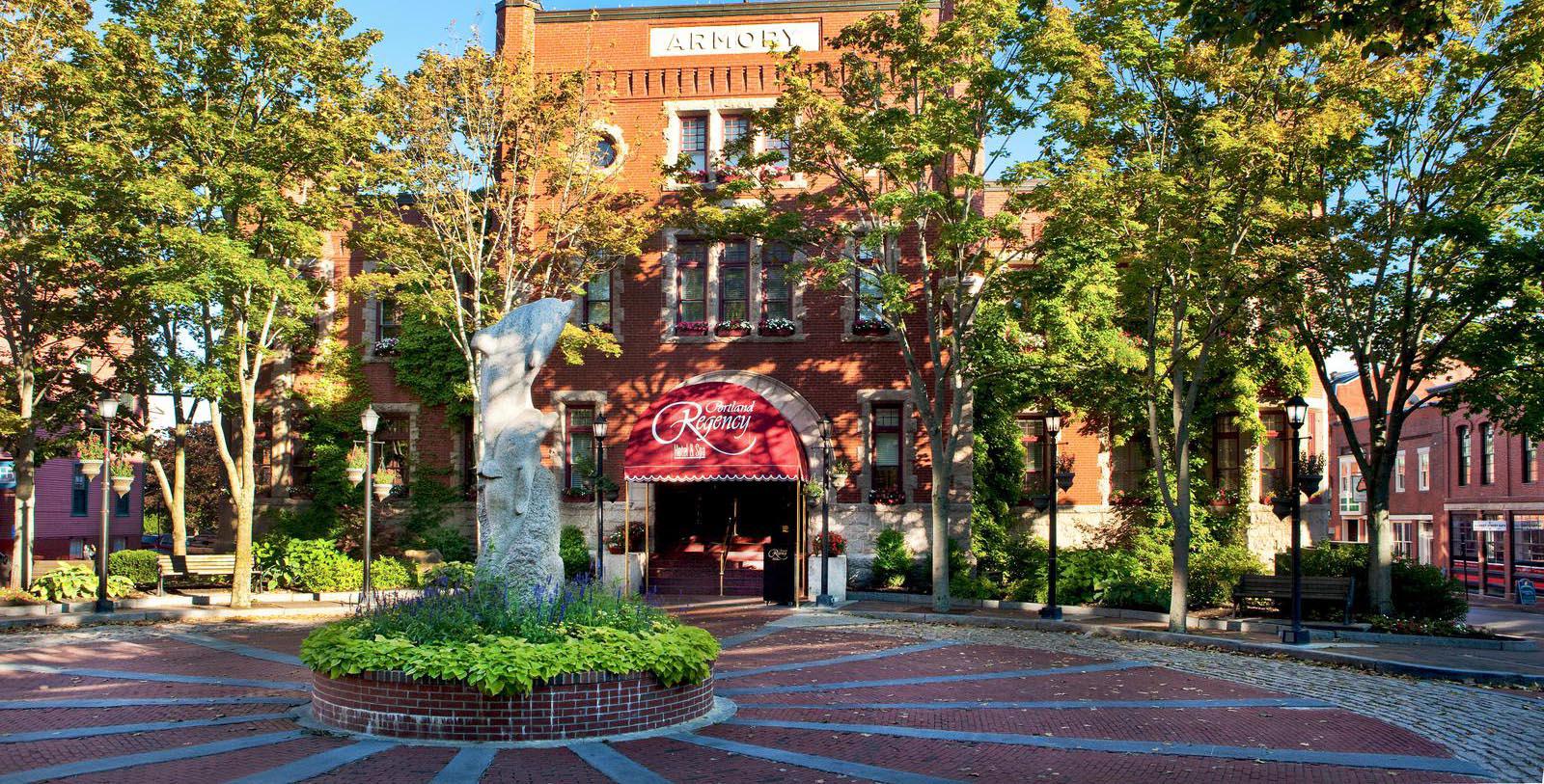 a brick building with trees and a statue in front of it