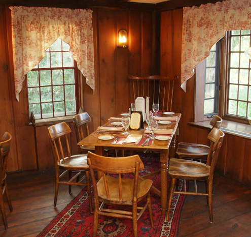 a table with chairs and a red rug in a room with windows