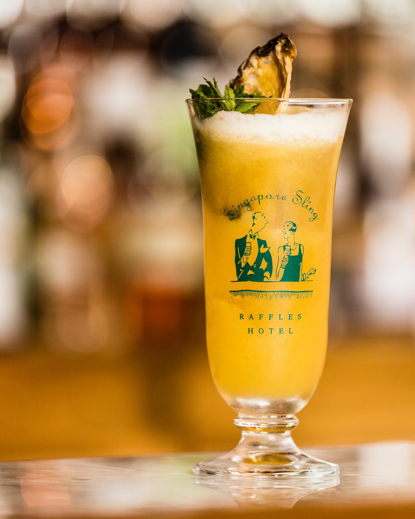 a glass of yellow liquid with a slice of pineapple on top