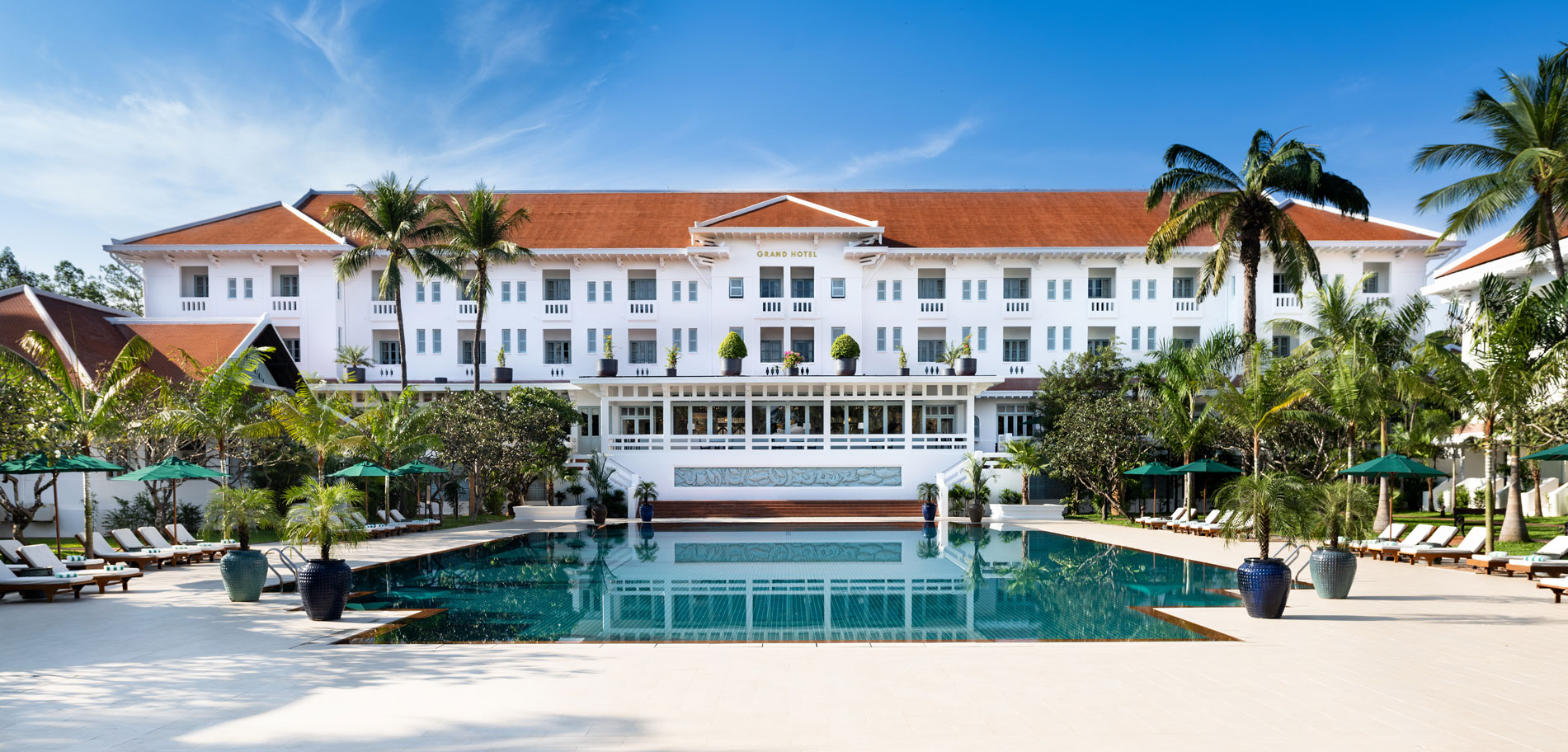 a large white building with a pool in front