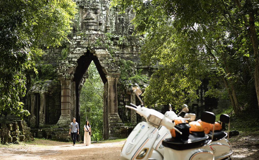 a couple walking in front of a stone archway