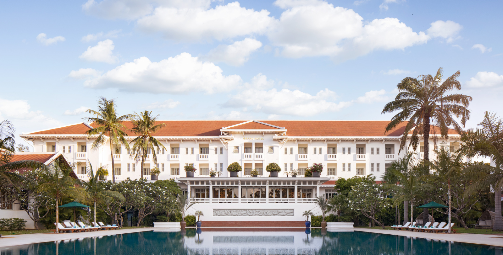 a large white building with a pool in front