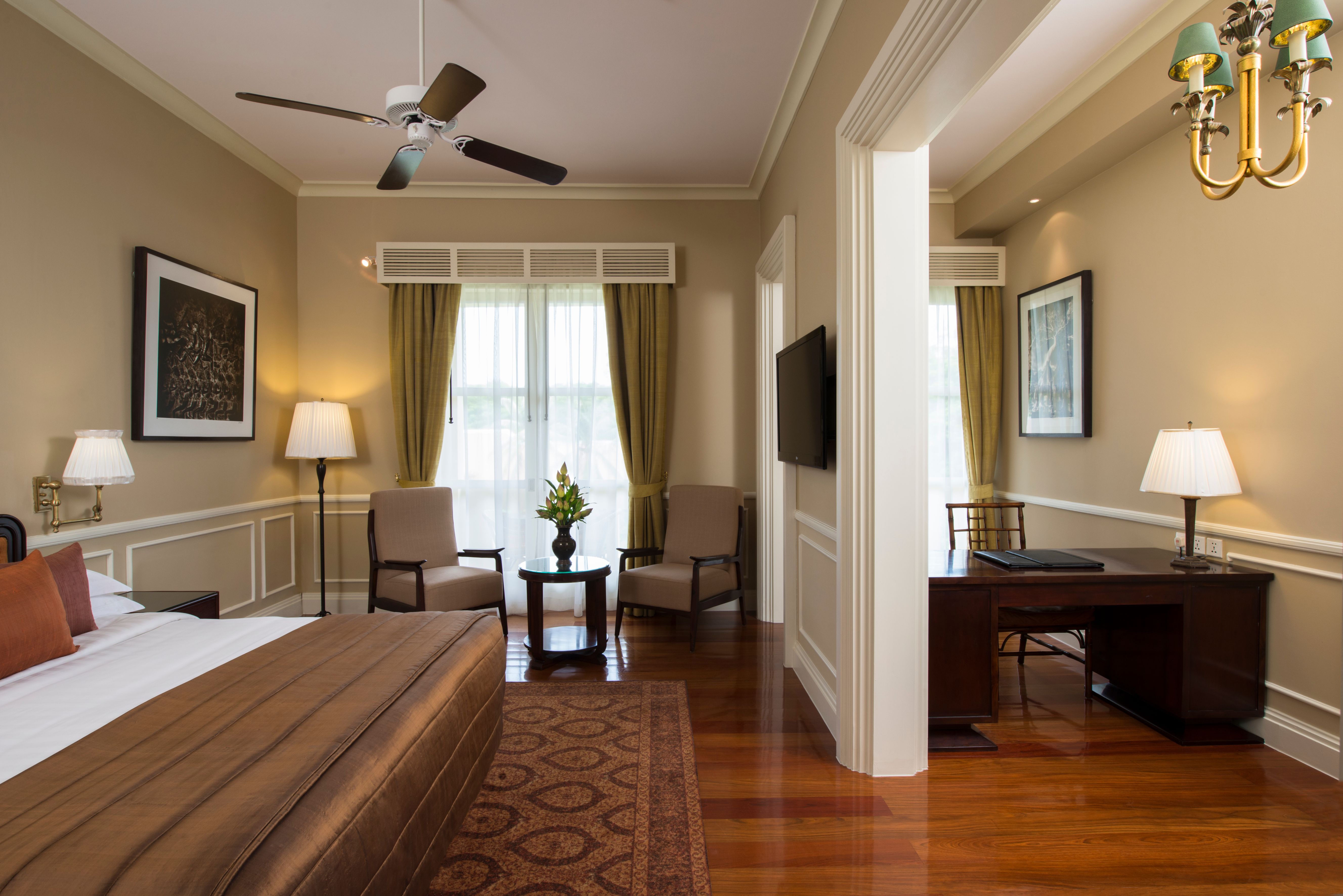 a room with a bed and a desk and a fan