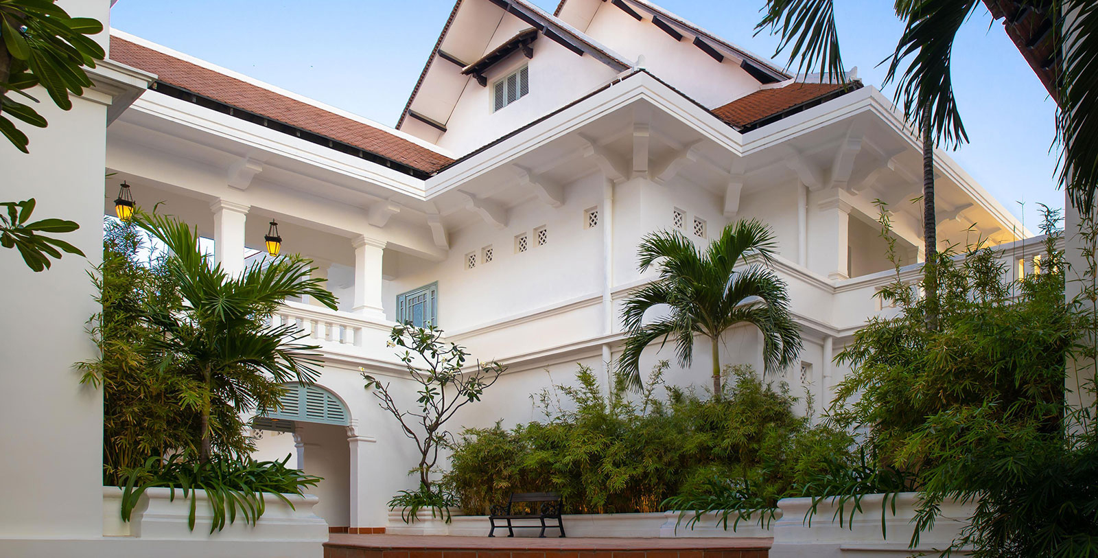 a white house with a bench and trees