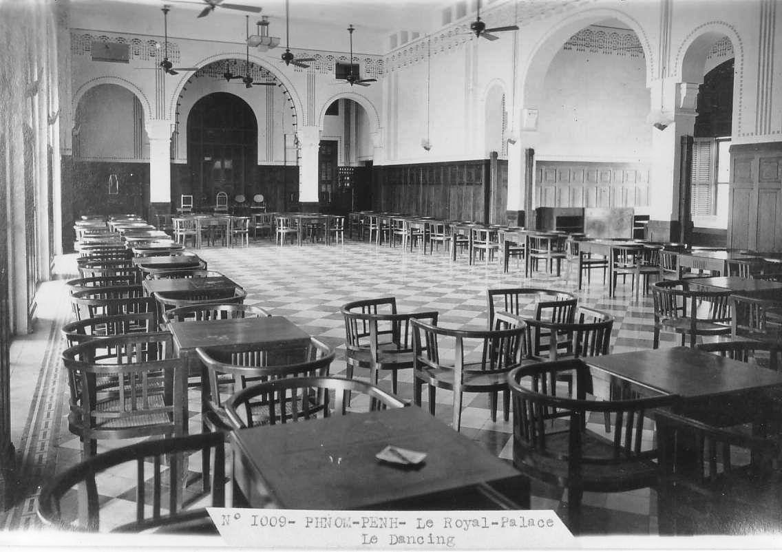 Vintage black-and-white photo of a grand hall labelled 'PHNOM-PENH - Le Royal-Palace Le Dancing', featuring checkered flooring, ceiling fans, arched doorways, and numerous wooden tables and curved-back armchairs.