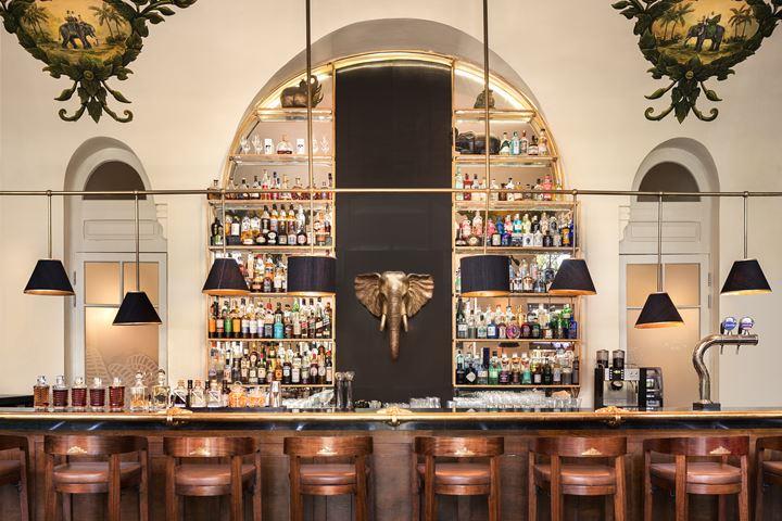a bar with shelves of liquor and chairs